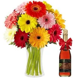 Shop Gerberas in a Glass Vase with a Bottle of Fruit Juice Online